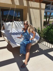 Lynn sitting down on a swinging chair outside